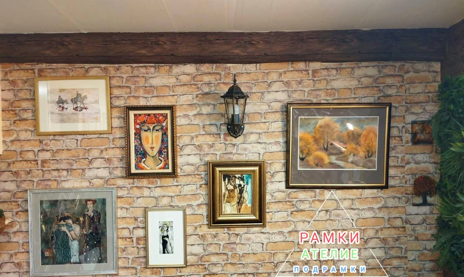 Рамкирани картини, подредени върху тухлена стена в ателието